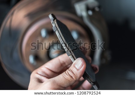 Car mechanic or serviceman checking a disc brake and asbestos brake pads it's a part of car use for stop the car for safety at front wheel this a used old part for change at car garage Royalty-Free Stock Photo #1208792524