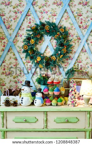 Christmas background with snowman, Christmas tree, wreath and cupcakes on wooden table, copy space. Festive snowmen with Christmas decorations