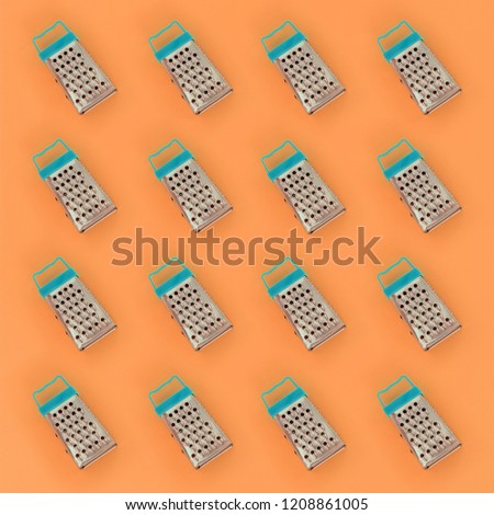 Small stainless steel graters lies on a pastel colored paper. Kitchen accessories. Tools for cooking. Flat lay top view