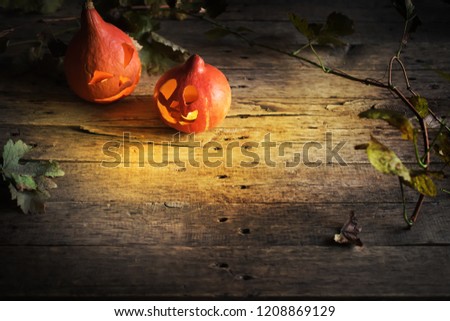 Burning Halloween pumpkin lantern head jack with leaves on wooden background