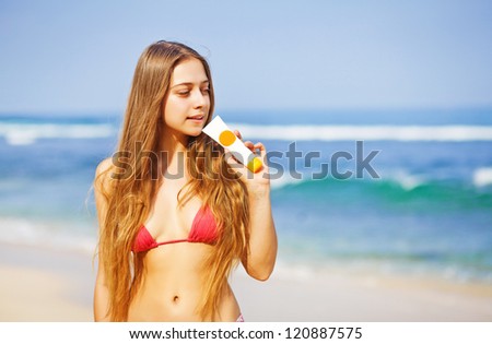 Portrait of woman taking skincare with sunscreen lotion at beach
