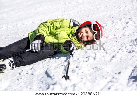 Child falling in the snow with skis