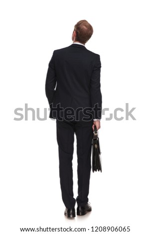 behind of curious businessman with suitcase looking up to side while standing on white background with a hand in pocket, full length picture