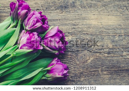 Ultraviolet tulip flowers on old rustic wooden table with place for text. Bouquet of purple spring tulips. Happy Mother's Day. Valentine's greetings card. Copy space. Top view.