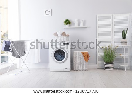 Laundry room interior with washing machine near wall Royalty-Free Stock Photo #1208917900