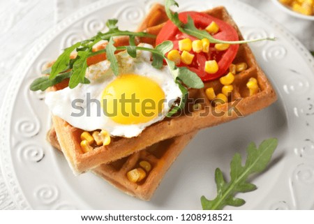 Delicious waffles with fried egg and vegetables on plate