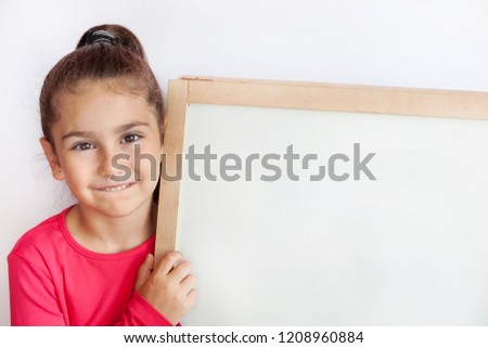 Smiling little girl with empty white board. Happy child. Space for text.