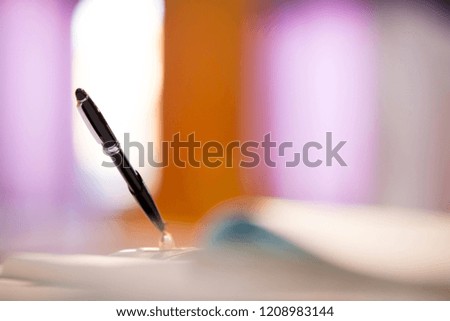 The black pen is embroidered on the pen, prepared to write or sign documents, as a background image that is blurred like a dream image.