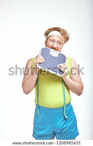 Funny picture of red haired, bearded, plump man on white background. Man holding the scales