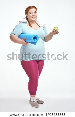 Funny picture of amusing, red haired, chubby woman on white background. Woman holding a mat.