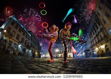 Night street circus performance whit two clowns, juggler. Festival city background. fireworks and Celebration atmosphere. Royalty-Free Stock Photo #1208989885