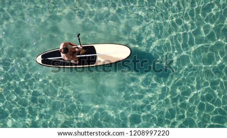 Aerial drone photo of unidentified man practicing stand up paddle in bamboo board or SUP in tropical exotic turquoise sea calm beach