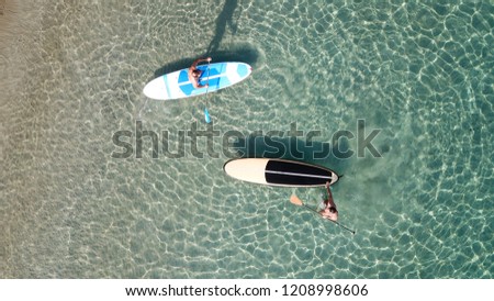 Aerial drone photo of 2 unidentified men practicing stand up paddle board or SUP in tropical turquoise calm beach