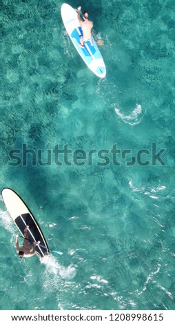 Aerial drone photo of 2 unidentified men practicing stand up paddle board or SUP in tropical turquoise calm beach