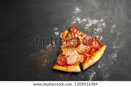 pieces of pizza pepperoni on dark black wooden board, traditional italian pizza