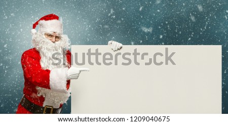 Christmas concept. Happy Santa Claus points to a blank banner with to copy space.  