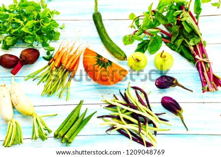 Autumn fresh tropical vegetables in flat lay on pastel blue wooden board, half of pumpkin, baby carrots eggplant, water cress, red and white radish, yard long bean and etc., healthy ingredient concept