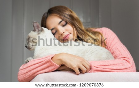 Attractive young brunette woman with her beautiful siamese cat.