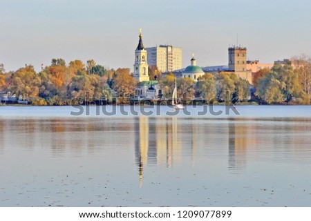 the old church and other buildings are reflected in the lake on an autumn day