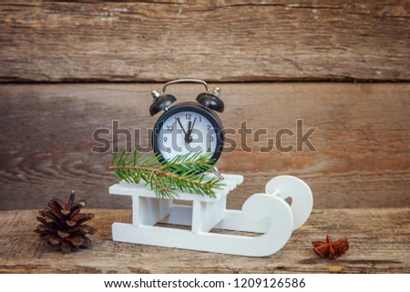 Christmas New Year composition winter objects alarm clock and sled on old shabby rustic wooden background. Xmas holiday december decoration copy space. Time for celebration concept