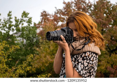 Woman with a camera in autumn park.