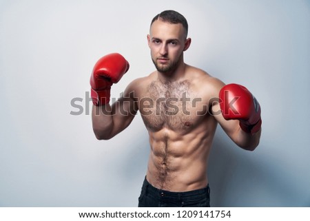 Muscular shirtless man wearing box gloves ready to struggle, looking at camera