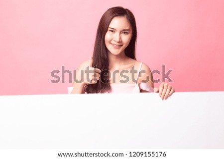 Young Asian woman show thumbs up with blank sign on pink background