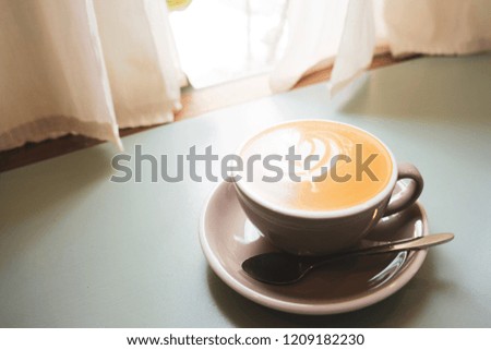 Morning coffee cup with latte art foam on light blue table ,Window lighting.