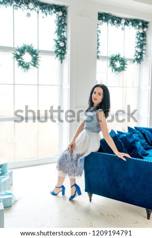 
young charming brunette in a refined dress in a stylish New Year's interior