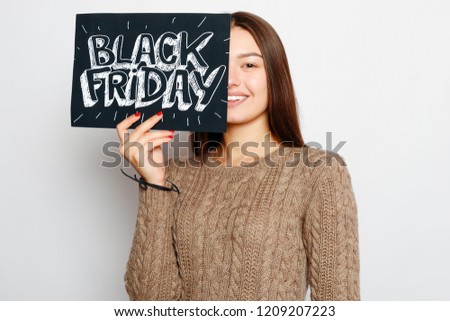 shopping, retail, black friday, sale, shopping and people concept - Young smiling brunette girl is holding a black friday sign. Black Friday sale.