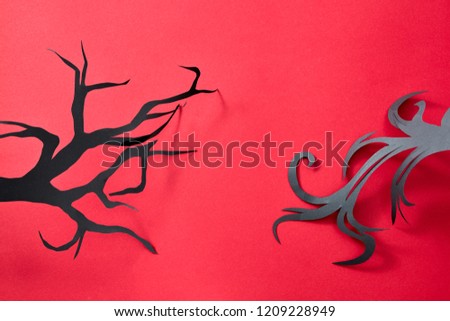 Pattern of black handcraft paper tree branches on a red background with space for text. Mystical Halloween postcard. Flat lay
