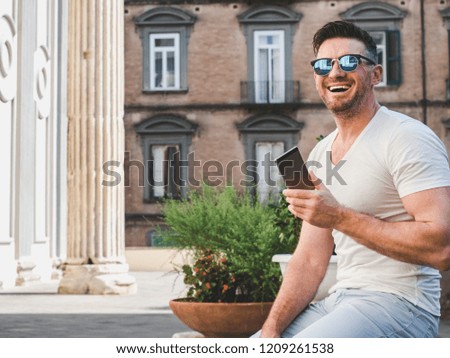 Attractive man with a phone on the background of bright, beautiful, old houses. Concept of communication, leisure and travel