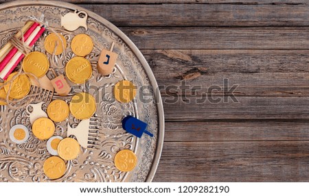 Hanukkah dreidels with Menorah and some Hanukkah coins and Hanukkah candles on a vintage wood background. Overhead or top view composition with copy space. Translation: Happy Holyday