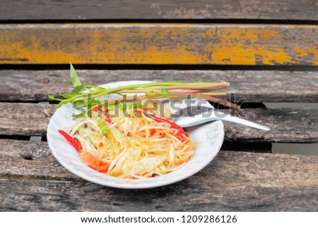 View of Papaya salad Thai cuisine spicy SOMTAM in a dish on the wooden texture background., Thai street food good test famous in Thailand.