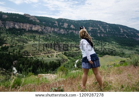 Blonde female photographer attemps to take a picture with her camera of the scenery of Wyoming Beartooth Highway