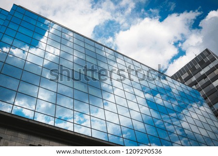 Glass corporate building with glass windows during the day. Sky reflections in the windows