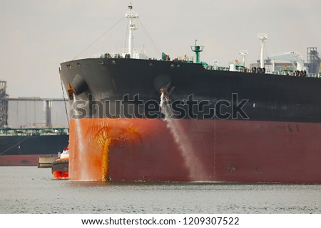 Large crude oil tanker ship pumping out ballast water when coming into port Royalty-Free Stock Photo #1209307522