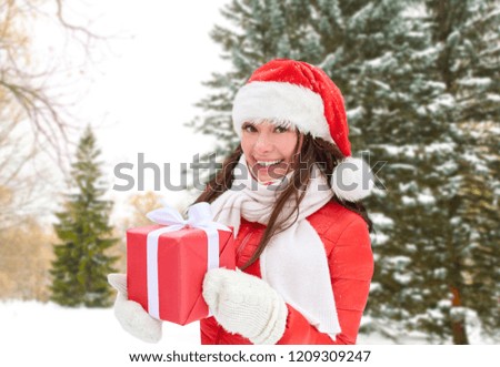 holidays and people concept - happy woman in santa hat with chrismas gift over winter forest background