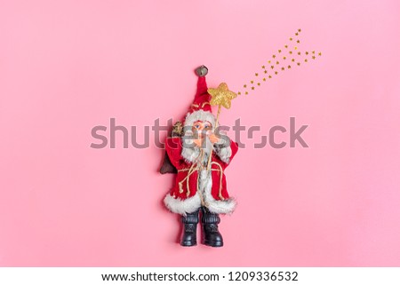 Santa Claus toy holds a staff with star and a Christmas tree on pink background of beige snowy night bokeh and blurred lights in the background Concept Happy New Year Copy space Banner,poster Flat lay