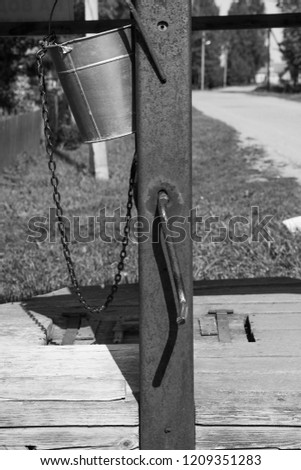 Black and white photo of a village well with a bucket