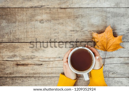 cup of tea in the hands of a child and a cozy autumn background. Selective focus. Kids.