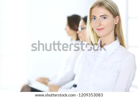 Attractive businesswoman at meeting or conference against the background of colleagues. Group of business people at work. Portrait of lawyer or secretary