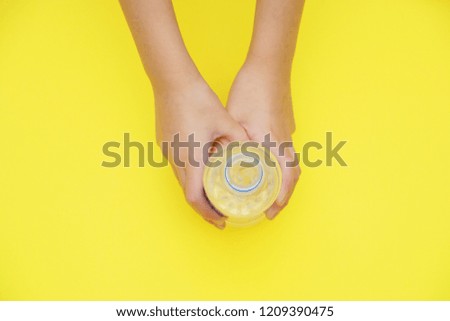 bottle of pure water in hands on yellow background with copy space on top.