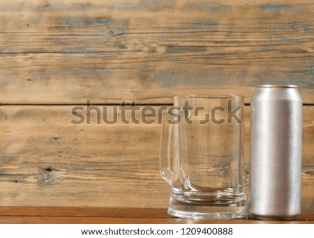 metallic can and glass blank mug of beer on a wooden background