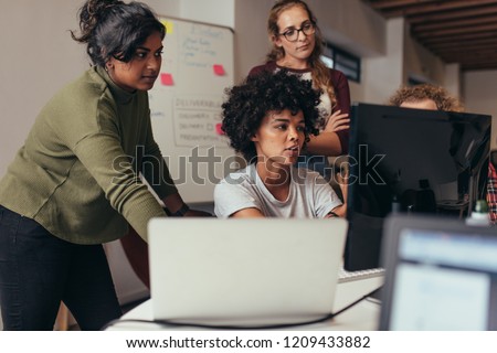 Software engineers working on project and programming in company. Startup business group working as team to find solution to problem. Woman programmer working on computer with colleagues standing by. Royalty-Free Stock Photo #1209433882
