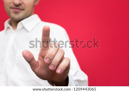 Attractive guy points his finger at the camera, front view, bright red background with copy space, for advertising, for records, close up