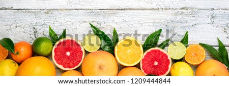 Citrus fruits background. Assorted fresh citrus fruits with leaves. Long web format. Top view