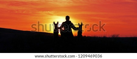 Silhouette of a man with dogs on the background of a beautiful incredible sunset