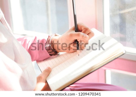Female hands with pencil writing on notebook