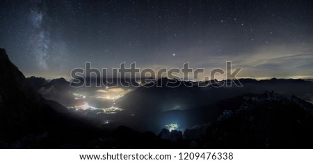 Milky way panorama shot from high above, with the still illuminated city